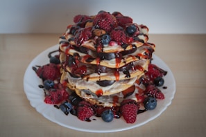A vibrant display of gourmet pancakes with fruits and syrup.