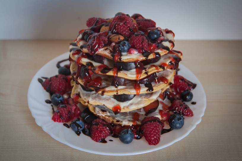 A stack of fluffy soufflé pancakes topped with fresh berries and a drizzle of syrup on a rustic wooden table.
