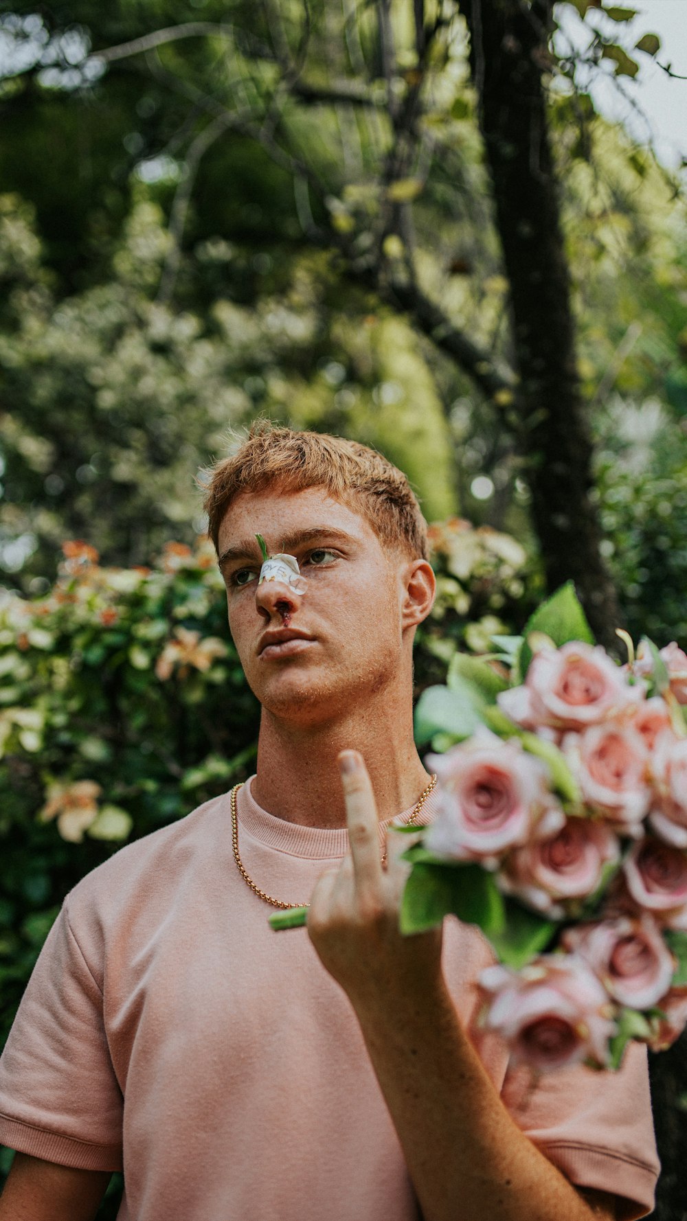 man in pink crew neck shirt holding pink and white roses