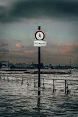 black and white street sign near body of water during daytime