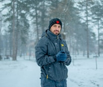 man in blue jacket standing on snow covered ground during daytime