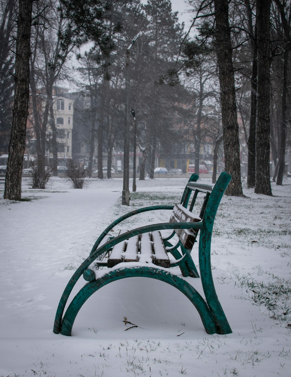 green wooden bench on snow covered ground