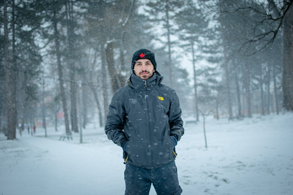 man in black jacket standing on snow covered ground