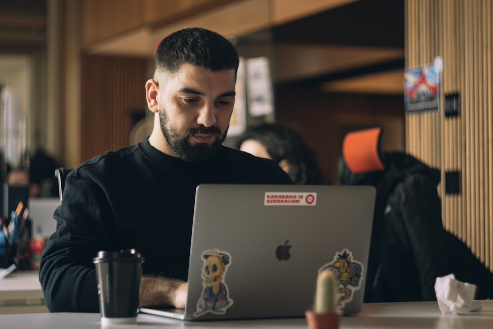 Hombre con camisa negra de cuello redondo usando MacBook