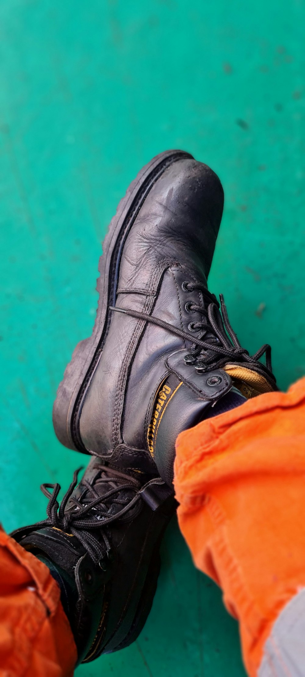 person wearing black leather work boot