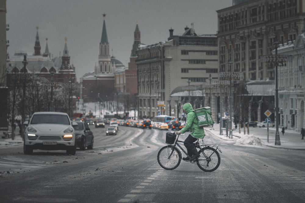 낮 동안 도로에서 자전거를 타는 녹색 재킷을 입은 남자
