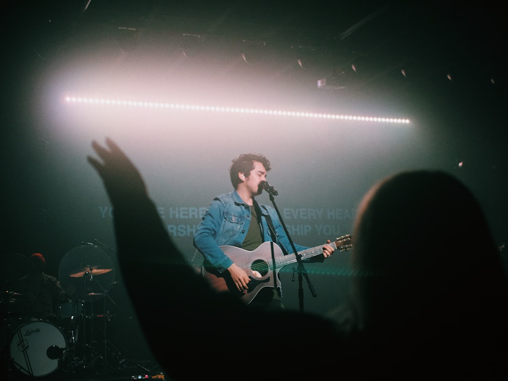 man in blue dress shirt playing guitar