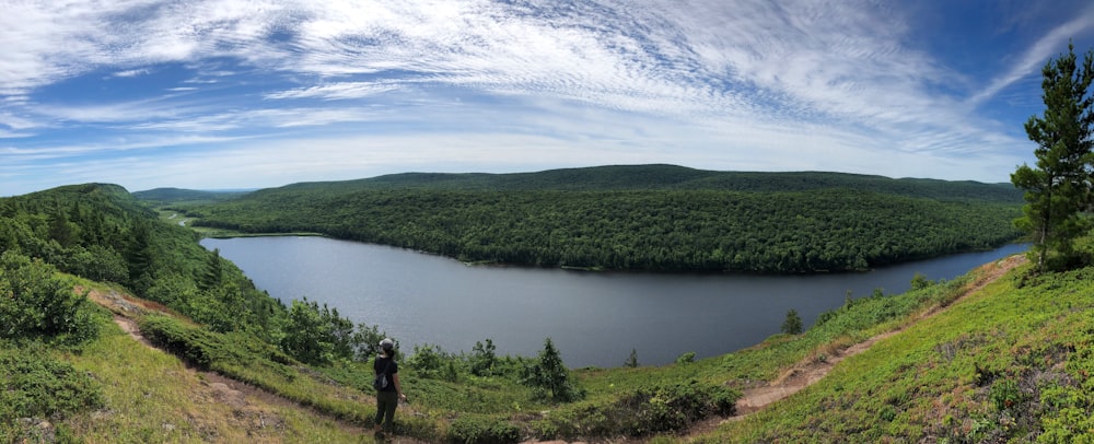 2 personas de pie en el campo de hierba verde cerca del lago bajo nubes blancas y cielo azul durante