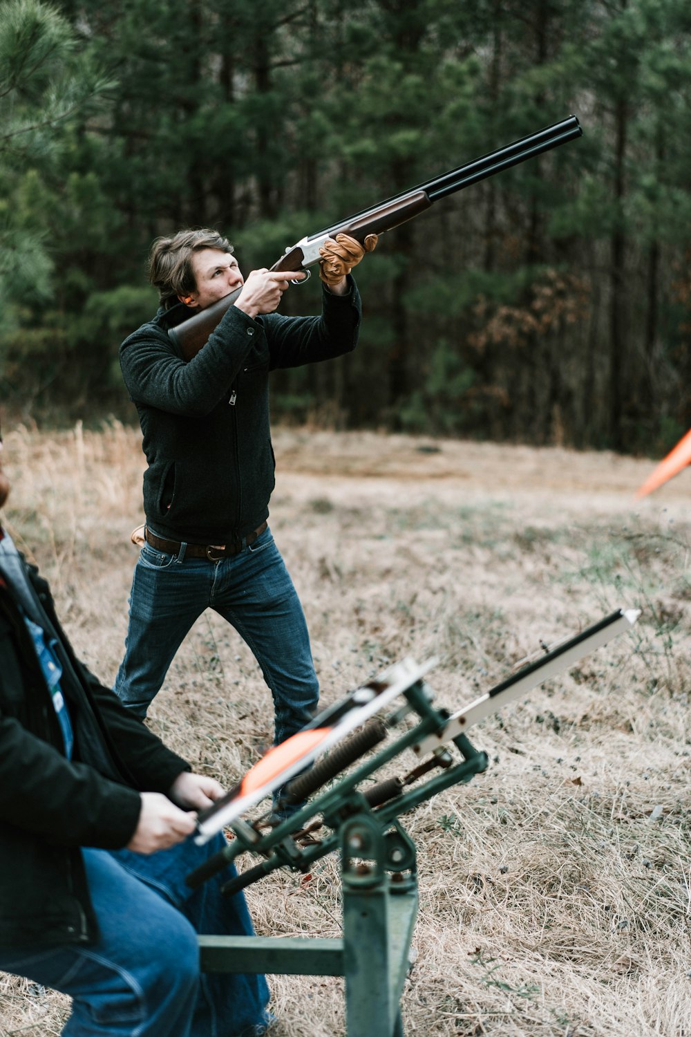 Mann in schwarzer Jacke und blauer Jeans mit Gewehr