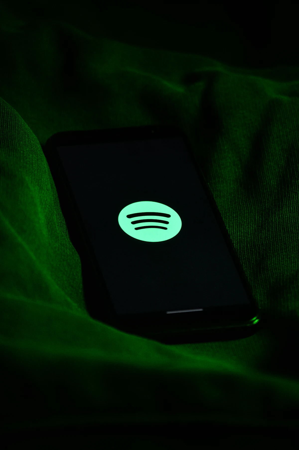 Layar ponsel menampilkan aplikasi Spotify dengan logo hijau khas siap memutar podcast favorit pendengar di mana saja