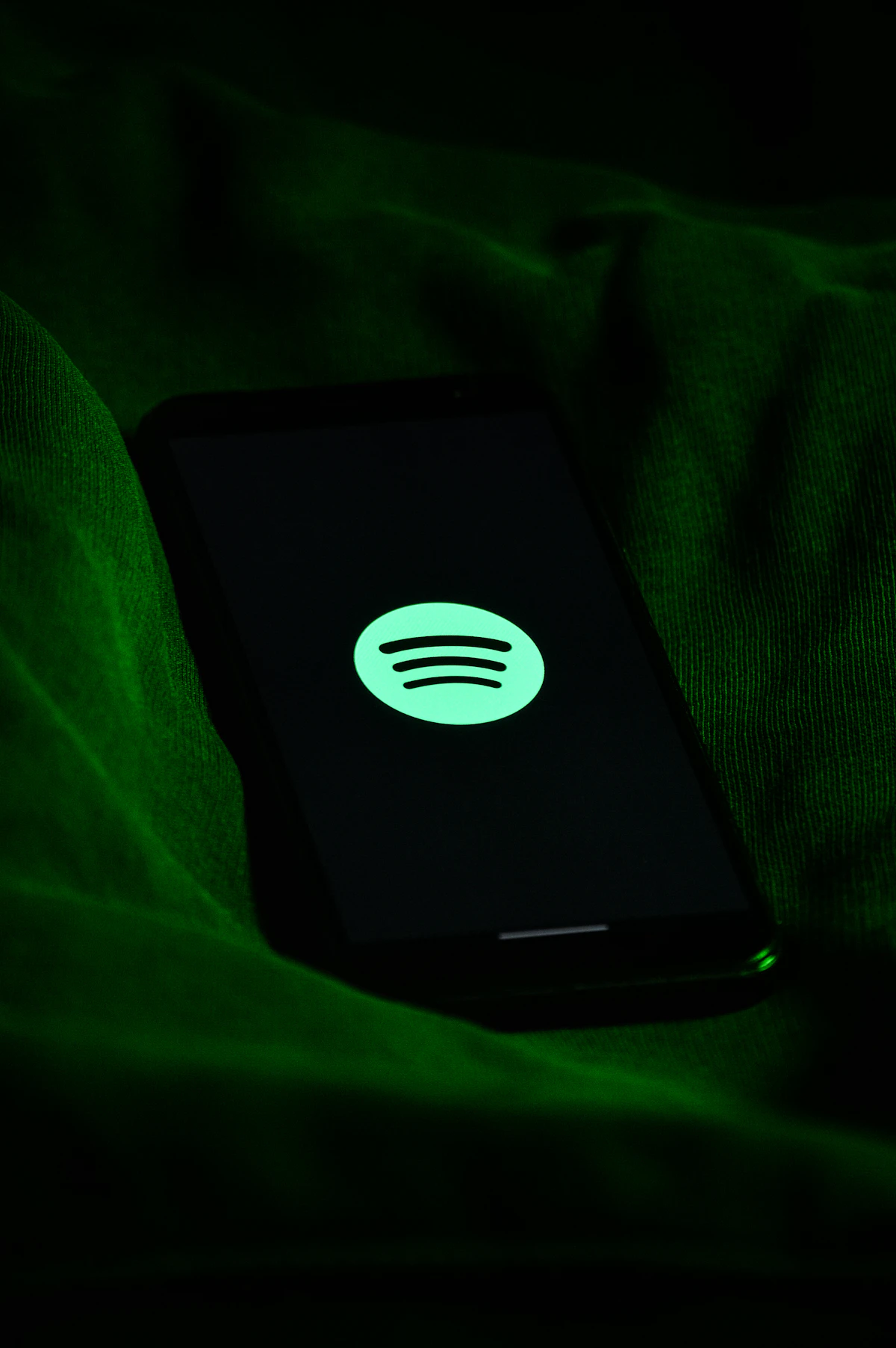Layar ponsel menampilkan aplikasi Spotify dengan logo hijau khas siap memutar podcast favorit pendengar di mana saja