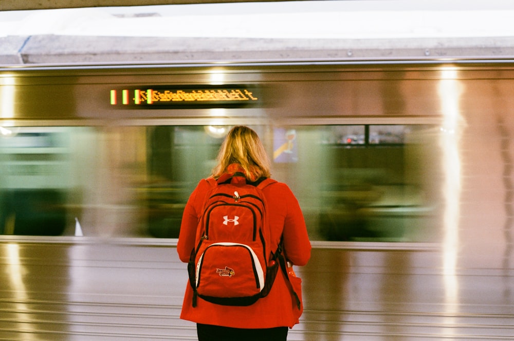 Frau im roten Langarmshirt steht vor dem Zug