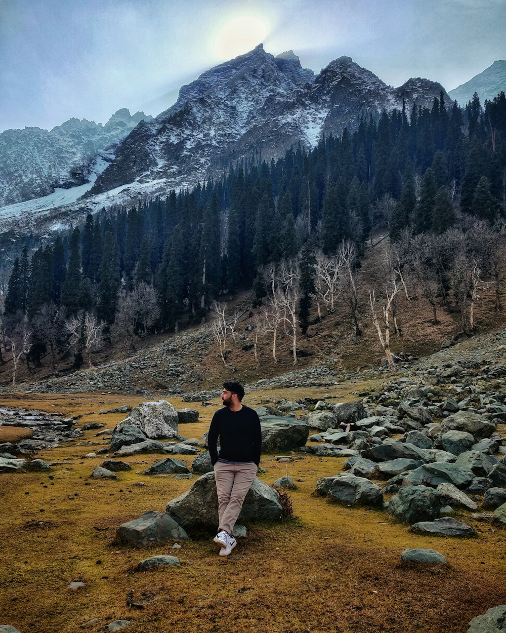 woman in black jacket and gray pants standing on brown dirt road during daytime