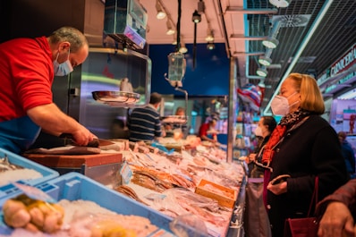 man in black and red jacket holding knife slicing meat