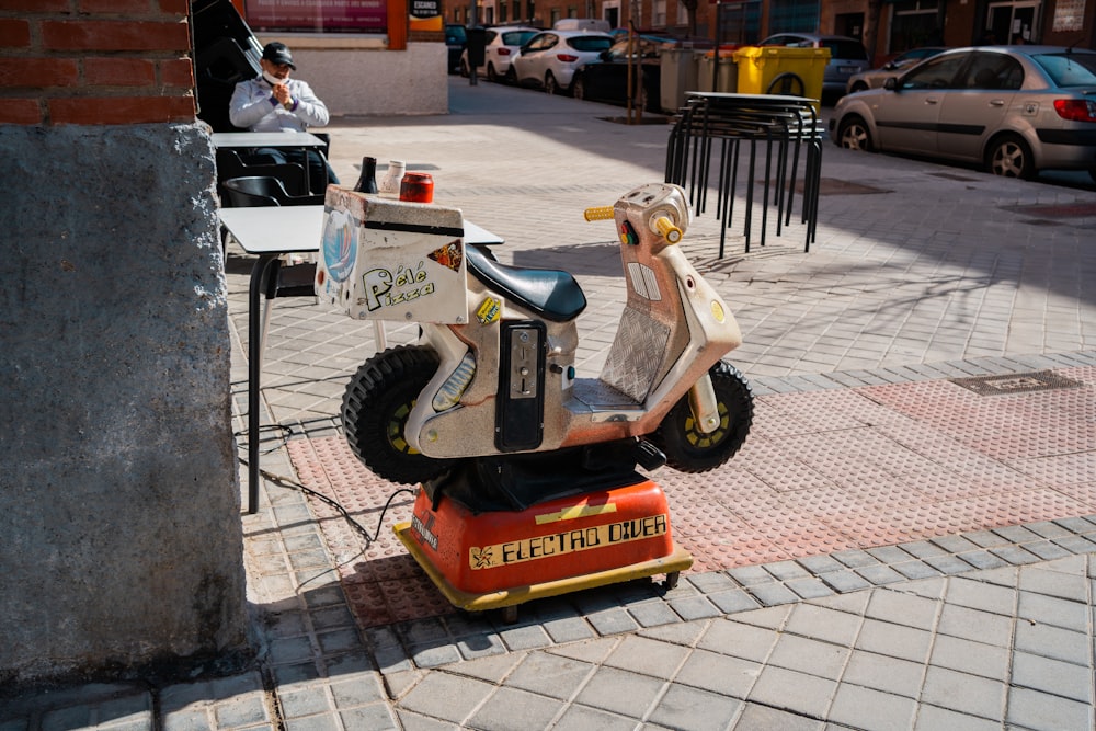 white and orange ride on toy on gray concrete floor