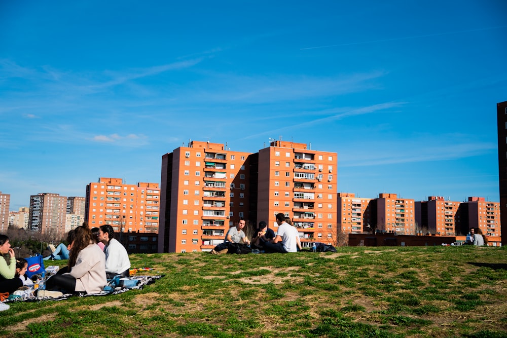 man in white shirt sitting on green grass field near city buildings during daytime