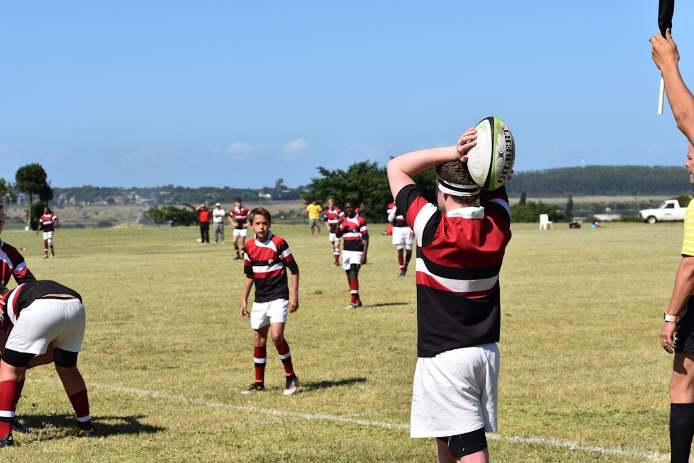 man in red and black jersey shirt holding white and black football