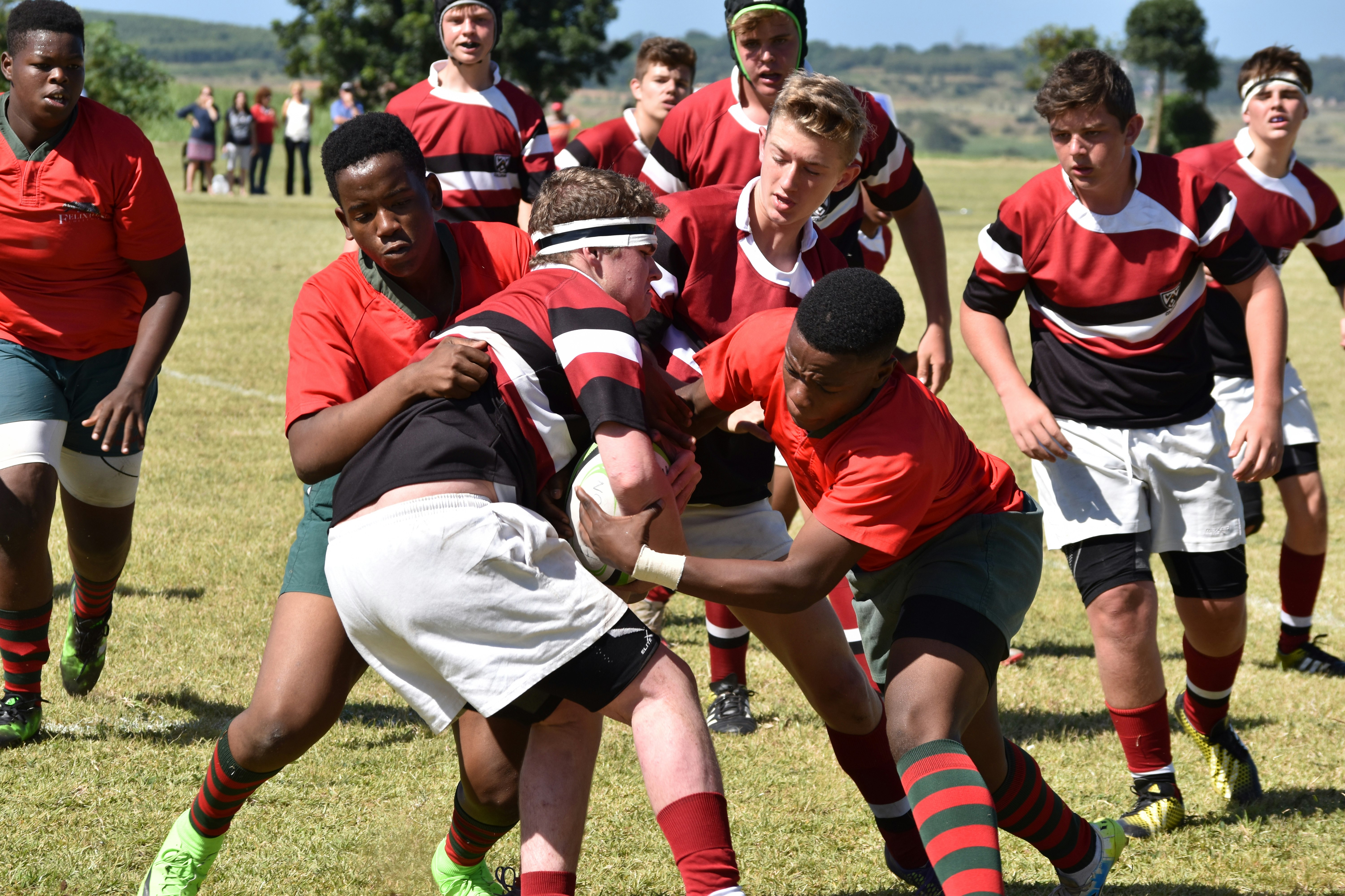 A young man struggles to hold onto the ball as he is tackled by other boys to wrestle the rugby ball away from him during a school boys rugby game in Durban South Africa. 