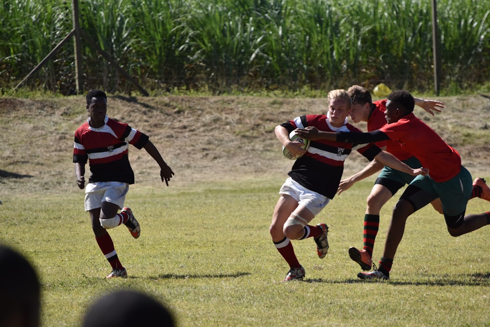 group of men playing soccer on green grass field during daytime