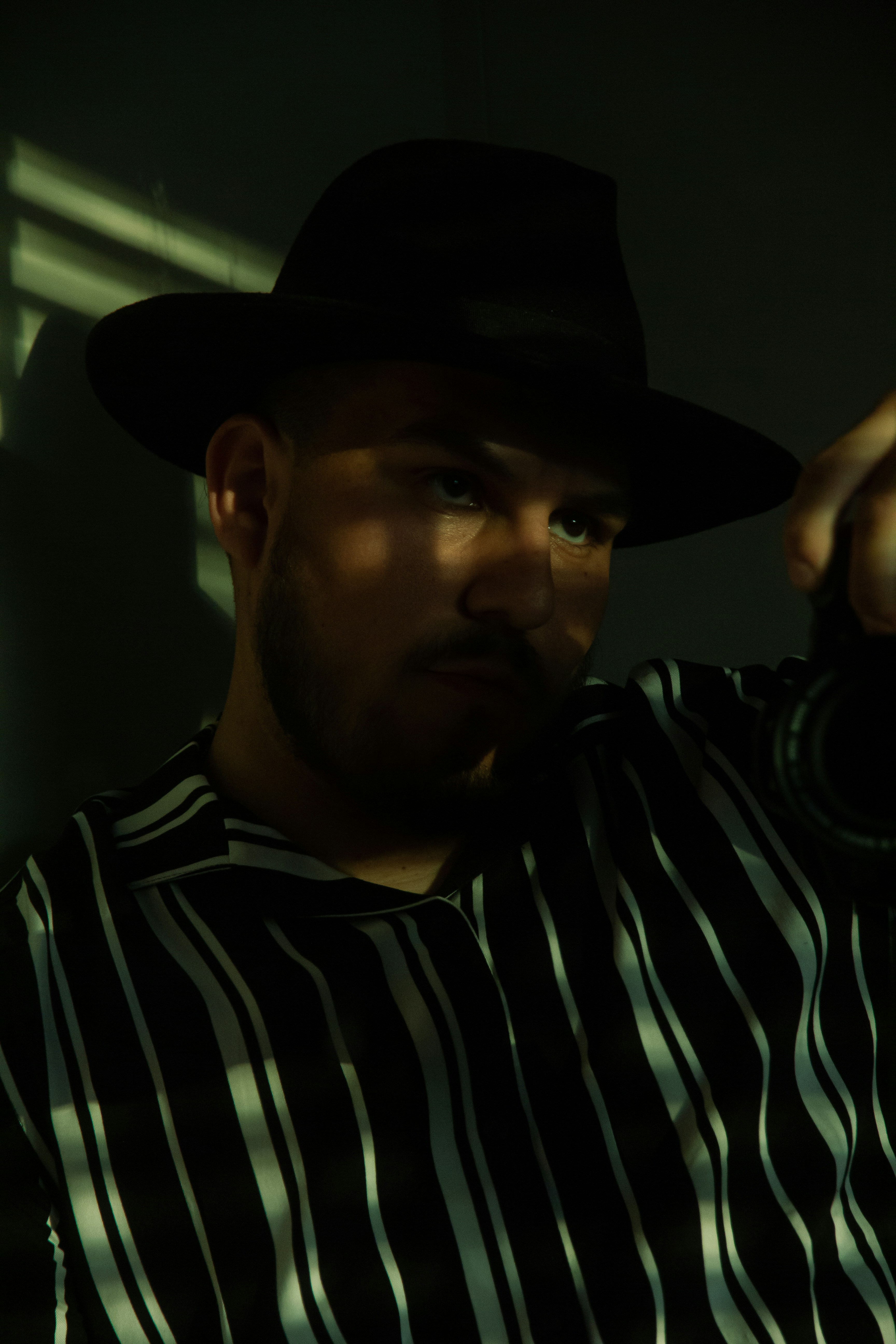 man in black and white striped polo shirt wearing black cowboy hat