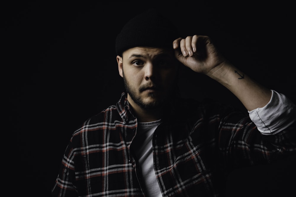 man in black and red plaid dress shirt wearing black cap