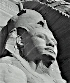 Intricate carvings on a sandstone statue of an Egyptian pharaoh.