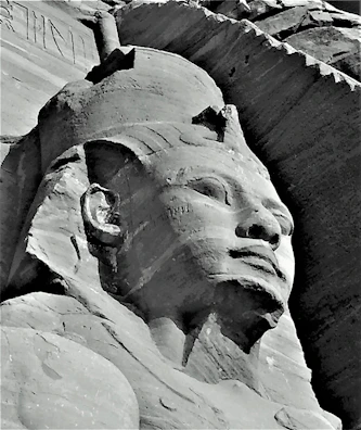 Intricate carvings on a sandstone statue of an Egyptian pharaoh.