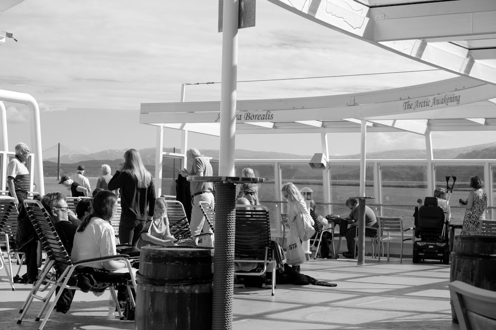 grayscale photo of people sitting on chair near table