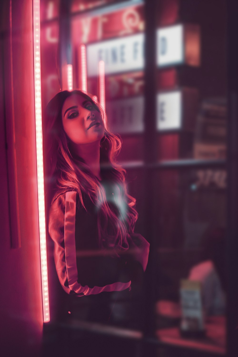 woman in red and black coat standing near glass window