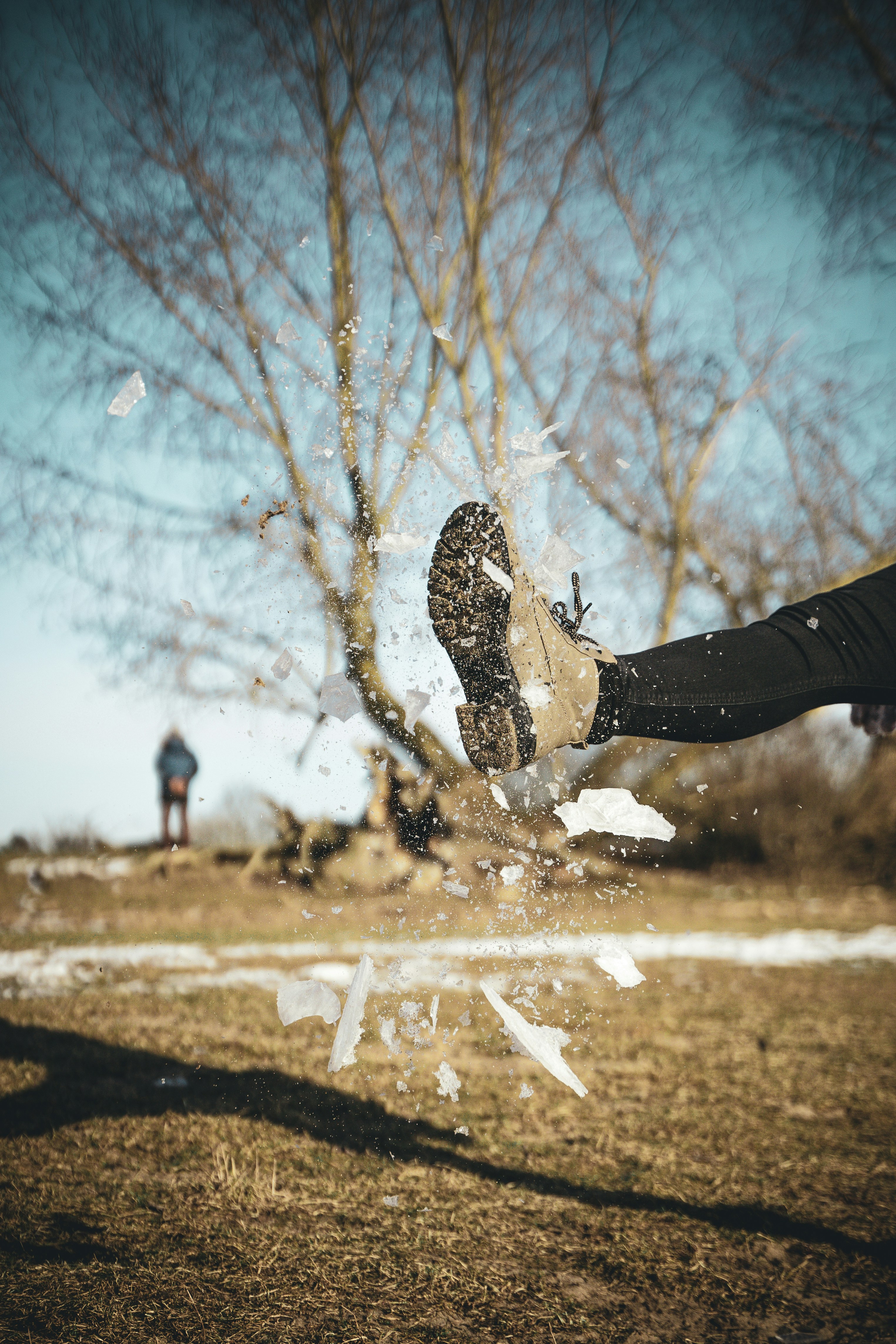 person in black pants and white and black sneakers sitting on brown field during daytime