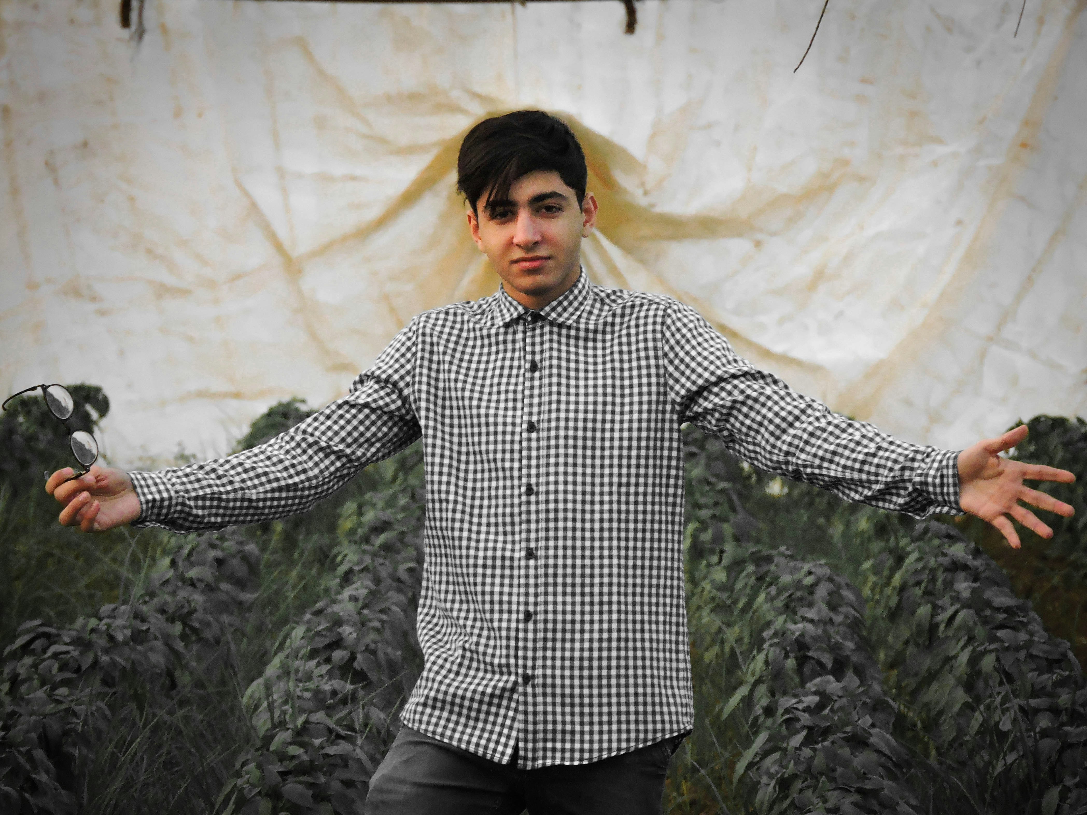 man in blue and white checked dress shirt standing near white wall
