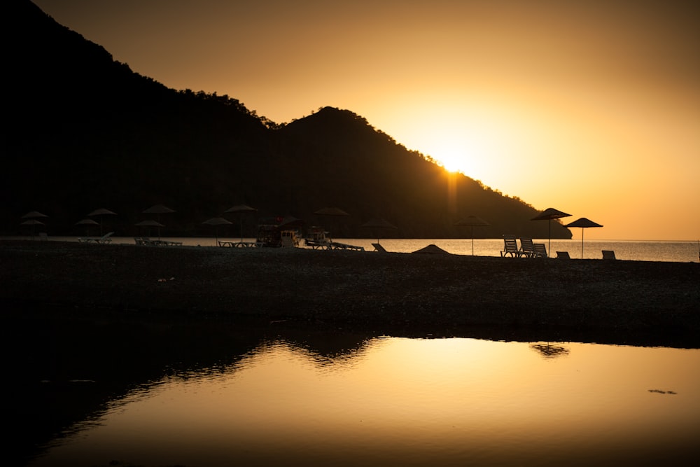 silhouette of mountain near body of water during sunset