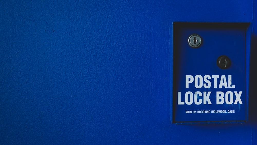 a blue wall with a sign that says postal lock box