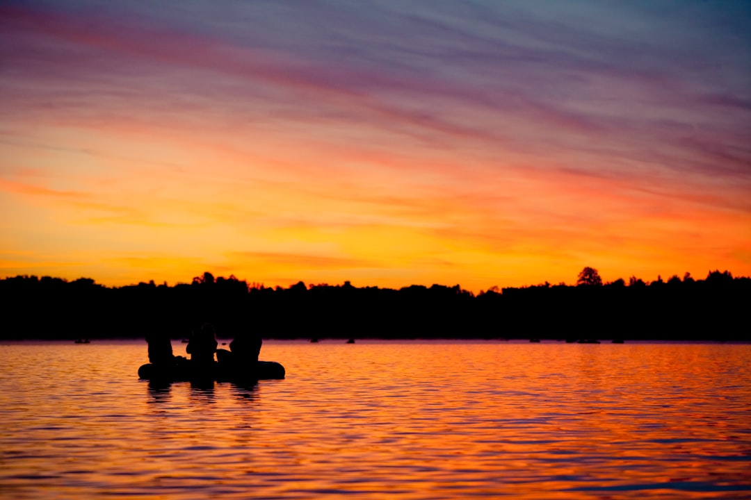 silhouette of 2 person on body of water during sunset