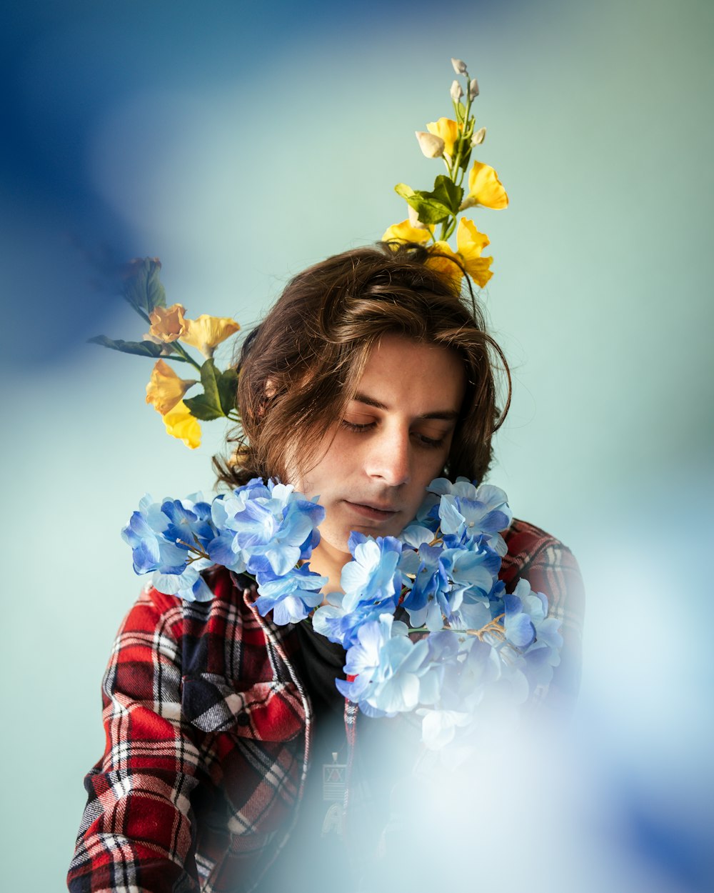 girl in red white and black plaid dress shirt holding yellow flowers