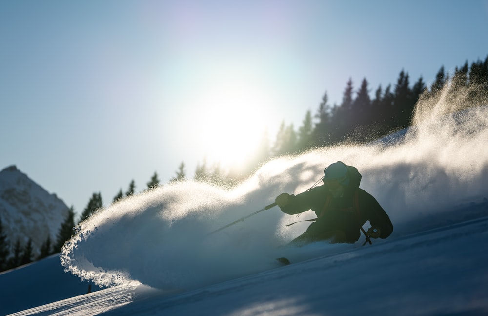pessoa em jaqueta preta e calças andando no snowboard durante o dia