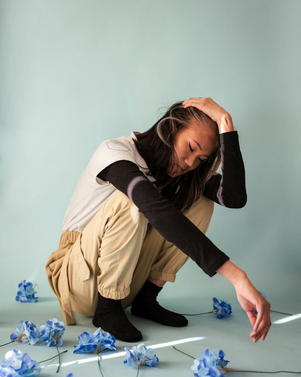 woman in brown coat and black pants sitting on white floor