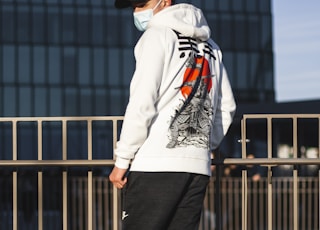 man in white hoodie and black pants standing on brown wooden floor during daytime