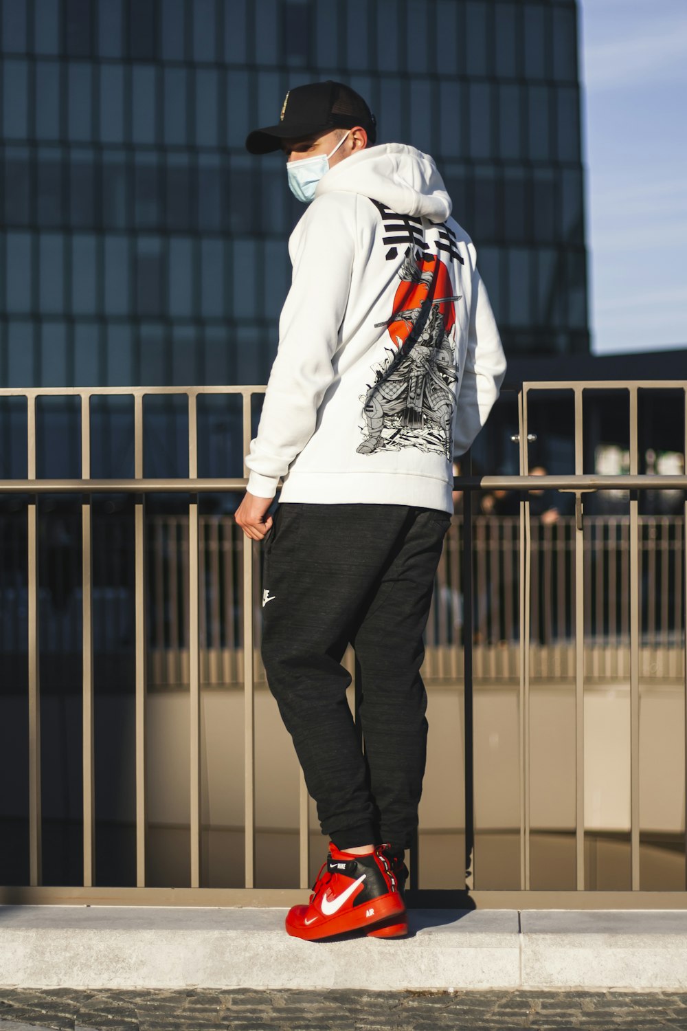 homme en sweat à capuche blanc et pantalon noir debout sur un plancher en bois brun pendant la journée