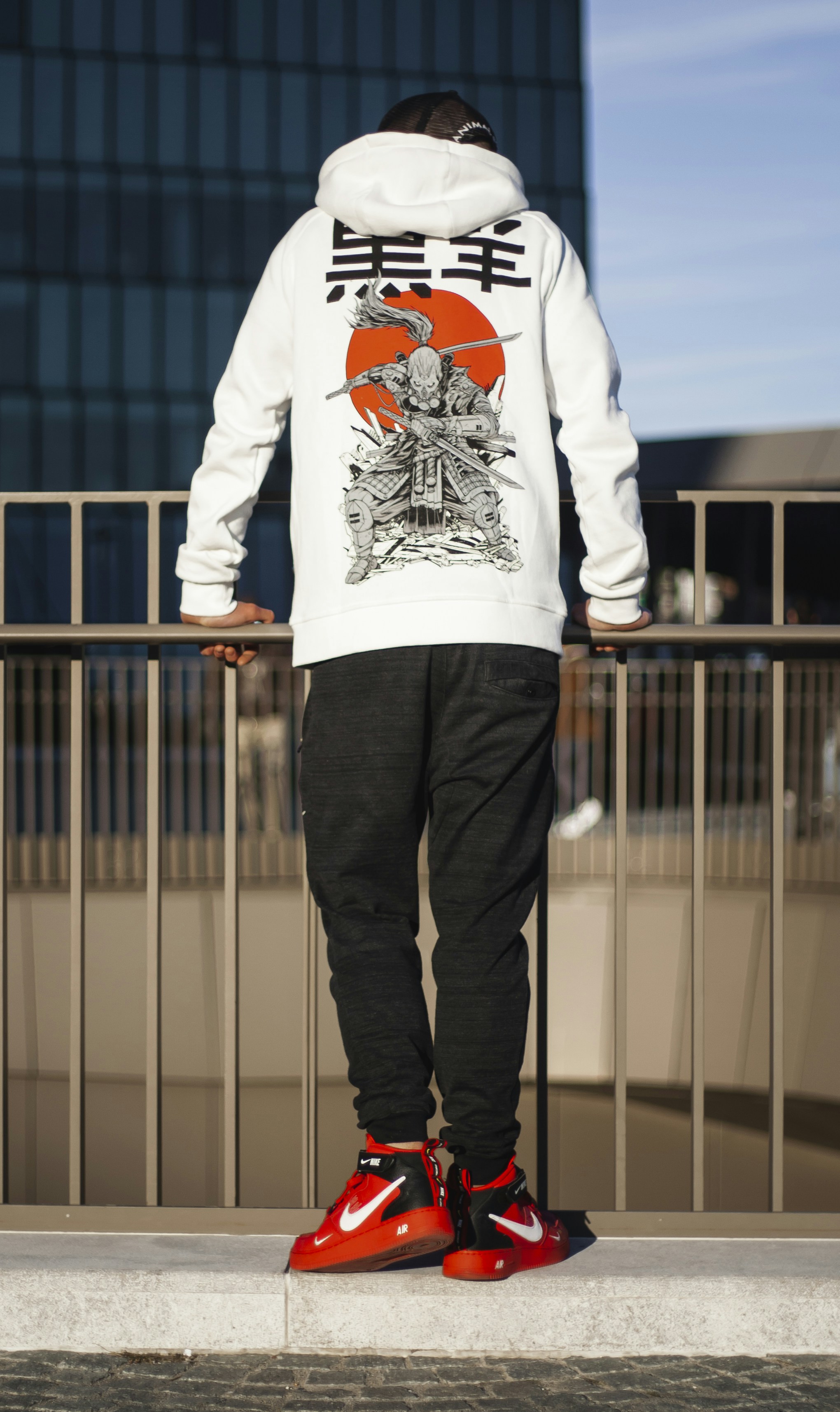 man in white and black long sleeve shirt and black pants standing beside black metal fence