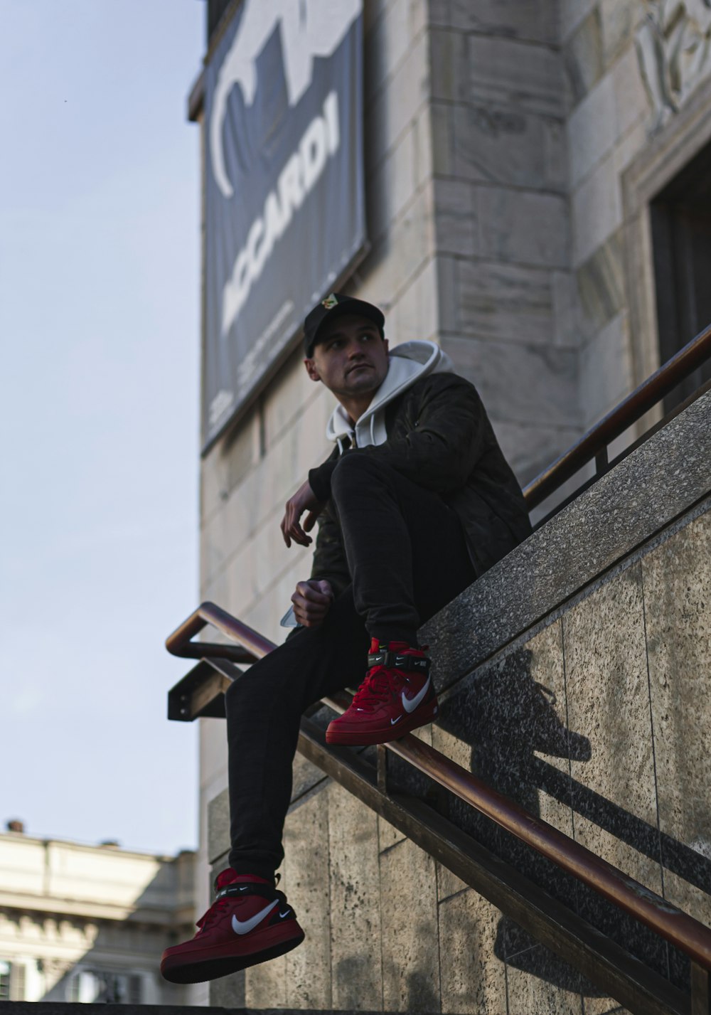 man in black jacket sitting on concrete bench during daytime