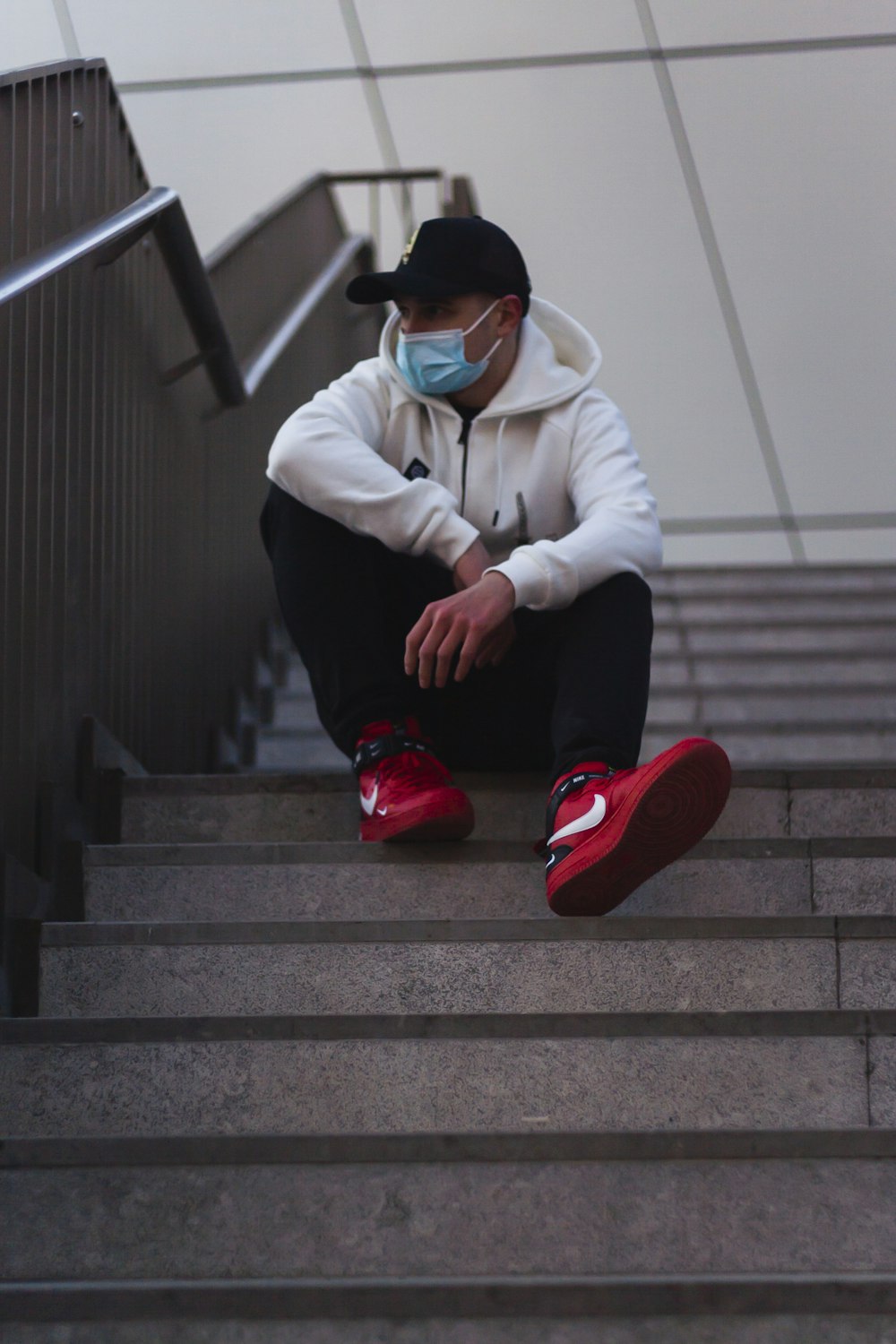 man in white jacket and black pants sitting on stairs