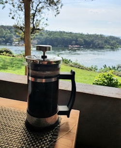 Close-up of a French press brewing rich coffee on a wooden table with natural light.
