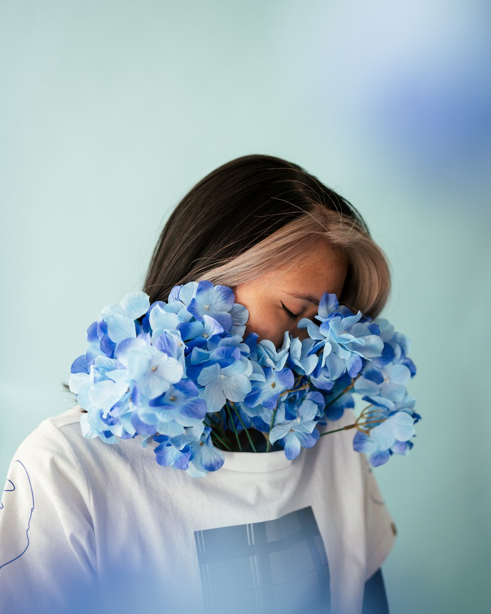 woman in white long sleeve shirt holding blue flowers