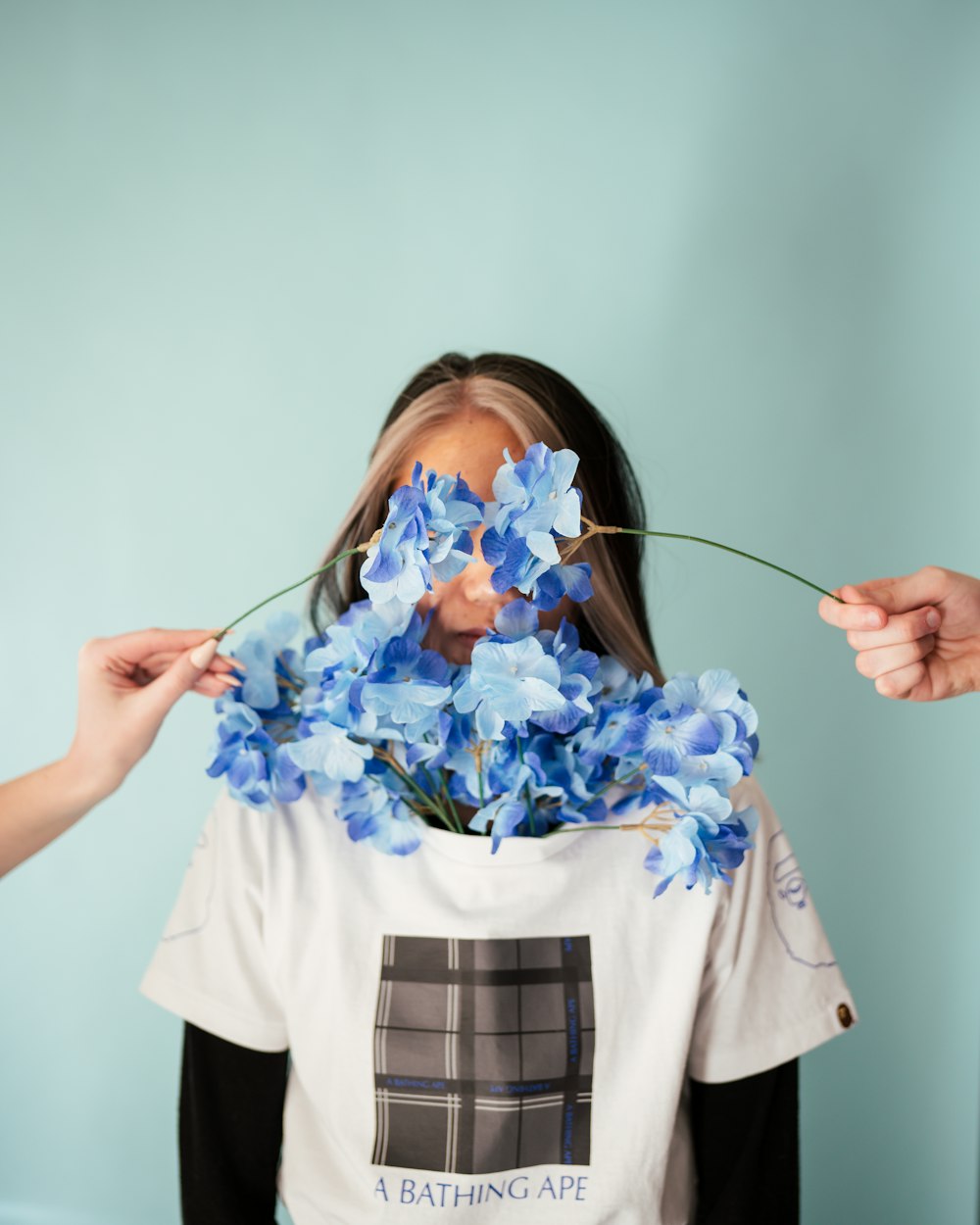 Mujer con camiseta blanca sosteniendo flores azules