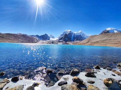 rocky shore with mountain in distance under blue sky during daytime