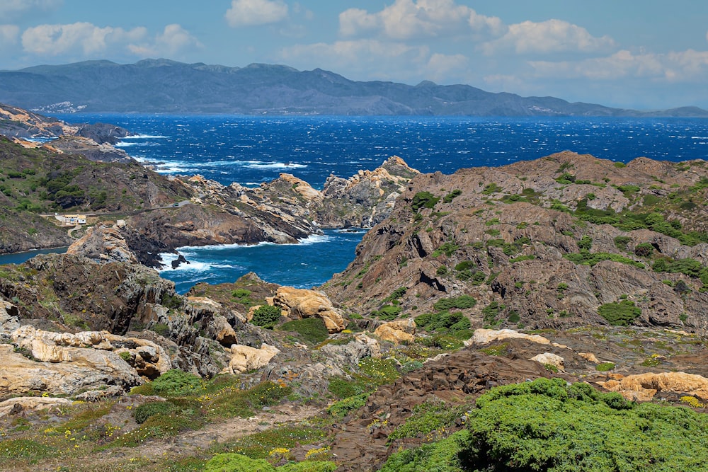 昼間の青空の下、青い海のそばの緑と茶色の山