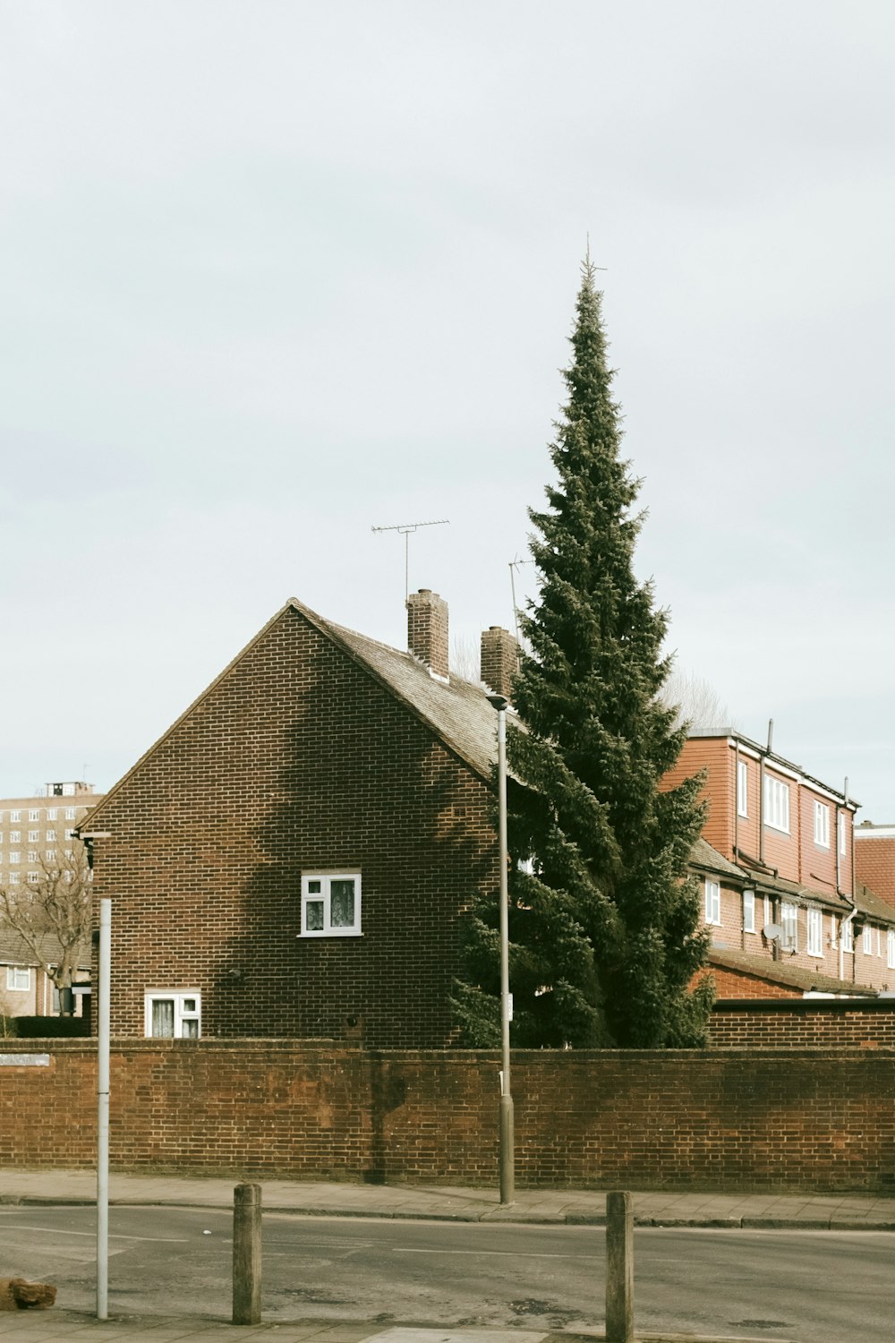 brown brick house near green trees under white sky during daytime