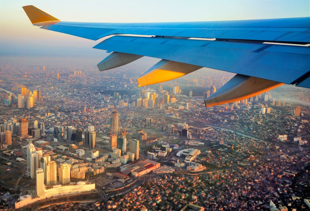 blue and white airplane wing above city buildings during daytime