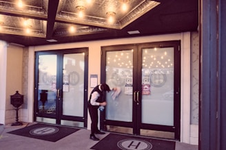 woman in white shirt standing near glass door